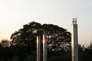 close up de colunas de concreto refletindo a luz do sol em um canteiro de obras com um fundo de céu azul foto