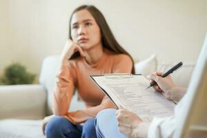 psicologia, depressão. triste, sofrimento ásia jovem mulher consultando com psicólogo, psiquiatra enquanto paciente aconselhamento mental com médico mulher levando notas às clínica. encorajando, terapia. foto