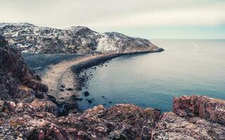 uma Rocha penhasco acima a água com uma maré litoral. Maravilhoso panorâmico montanha panorama em a barents mar. foto