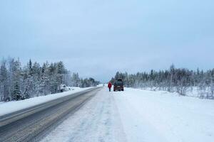 a carro é estacionado em a lado do uma inverno estrada. ártico neve em linha reta inverno estrada foto