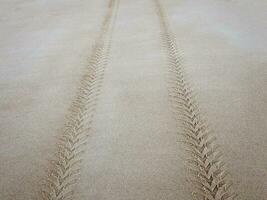 pneu piso marca em a mar areia estendendo para dentro a distância foto