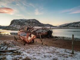 a velho oxidado pescaria barco abandonado de uma tempestade em a costa. cemitério do navios, velho pescaria Vila em a costa do a barents mar, a cola Península, teriberka foto