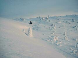 moto de neve em campo de neve. inverno esporte. coberto de neve montanhas e nublado clima com nevasca dentro khibiny montanhas, Rússia. foto