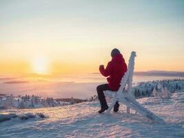 feliz homem com uma copo do chá às nascer do sol. Visão em a congeladas mar a partir de acima. café a partir de a ao ar livre. Nevado montanha fundo. inverno feriados, turismo, viagem e pessoas conceito. foto