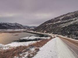 rodovia entre a ártico colinas. norte inverno estrada, virar em a estrada. magenta polar pôr do sol. foto