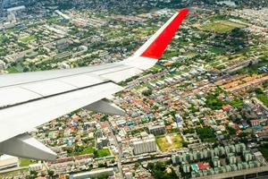 closeup asa de avião enquanto voava no ar com a paisagem urbana abaixo foto