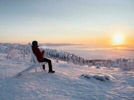 chá às uma gelado pôr do sol. homem com uma copo do chá às nascer do sol. café a partir de a ao ar livre. Nevado montanha fundo. inverno feriados, turismo, viagem e pessoas conceito. foto