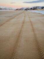 pneu piso marca em a mar areia estendendo para dentro a distância foto