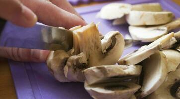 dona de casa cortes champignon dentro a cozinha, cozinhar fatias cogumelos com uma faca, fatias do champignons, cogumelo fatiamento foto