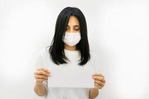 mulher com máscara segurando um cartaz em branco foto