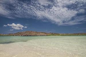 água do mar clara com montanhas ao fundo e céu azul com nuvens na península de baja, baja califórnia foto