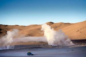 paisagem do deserto boiviano ensolarado com enormes gêiseres fumegantes foto