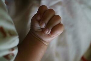 1 mão do uma recém-nascido dentro uma ganancioso posição com a polegar dentro foto