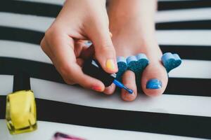 a criança tintas dele unhas dos pés com brilhante azul verniz. pequeno menina faz uma pedicure. beleza salão jogo. crianças entretenimento. foto
