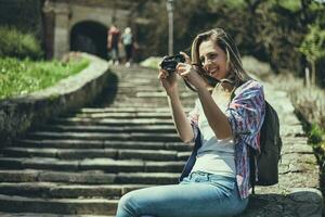 jovem turista mulher sentado de a escadas levando fotos