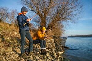 pai e filho estão pescaria em ensolarado inverno dia foto