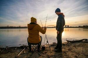 pai e filho estão pescaria em ensolarado inverno dia foto