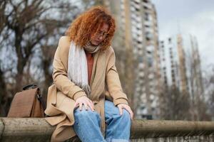 chateado jovem mulher com sardas e encaracolado gengibre cabelo ao ar livre foto