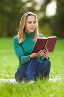 uma mulher gastos Tempo ao ar livre e lendo uma livro foto