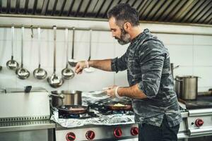 uma chefe de cozinha é preparando uma refeição dentro a do restaurante cozinha. foto