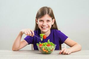 uma menina comendo uma salada foto
