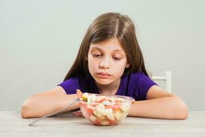 uma menina comendo uma fruta salada foto