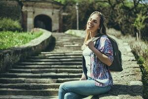 feliz jovem turista mulher sentado de a escadas foto