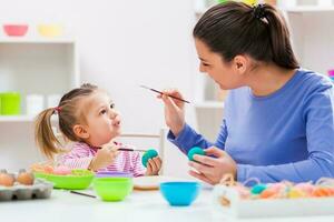 uma mãe e filha pintura ovos foto