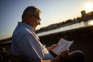 Senior homem lendo uma livro lado de fora foto