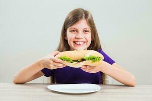 uma menina comendo uma sanduíche foto