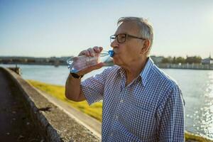 Senior homem bebendo água ao ar livre foto