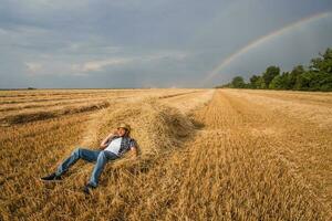 uma agricultor em pé dentro uma trigo campo depois de uma bem sucedido colheita foto