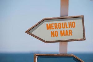 placa de sinalização com a frase mergulhar no mar escrita em português no rio de janeiro foto