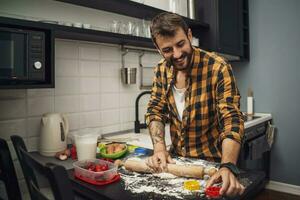 uma homem cozimento biscoitos dentro a cozinha foto