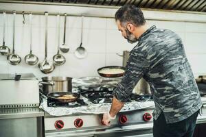 uma chefe de cozinha é preparando uma refeição dentro a do restaurante cozinha. foto
