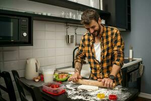 uma homem cozimento biscoitos dentro a cozinha foto