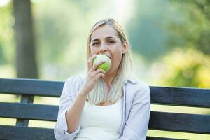 uma mulher comendo a maçã em a parque foto