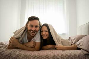 uma jovem casal deitado dentro cama foto
