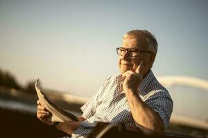 Senior homem lendo uma livro lado de fora foto