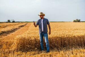 uma agricultor examinando uma trigo campo foto