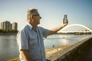 Senior homem segurando a telefone lado de fora foto