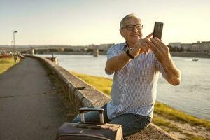 Senior homem segurando a telefone lado de fora foto