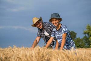 pai e filho estão em pé dentro seus trigo campo foto