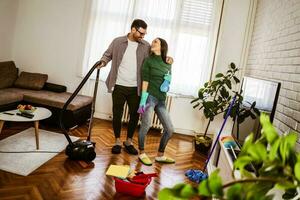 jovem casal é limpeza seus apartamento foto