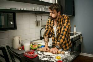 uma homem cozimento biscoitos dentro a cozinha foto