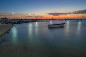 pôr do sol em la paz baja california sur mexico com um barco no mar e o reflexo das luzes na água perto da praia foto