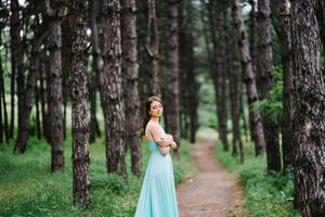 garota feliz em um vestido longo turquesa em um parque verde foto