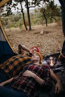 casal jovem, um rapaz e uma rapariga com chapéus de malha brilhantes, pararam num parque de campismo foto