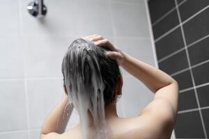 mulher lavando cabelo com xampu e chuveiro dentro a banheiro. ai gerado foto