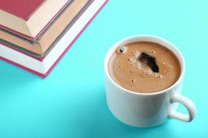 uma xícara de café fresco e livros sobre fundo azul foto